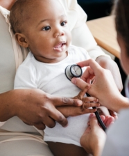a baby being held as doctor hold a stethoscope against their chest